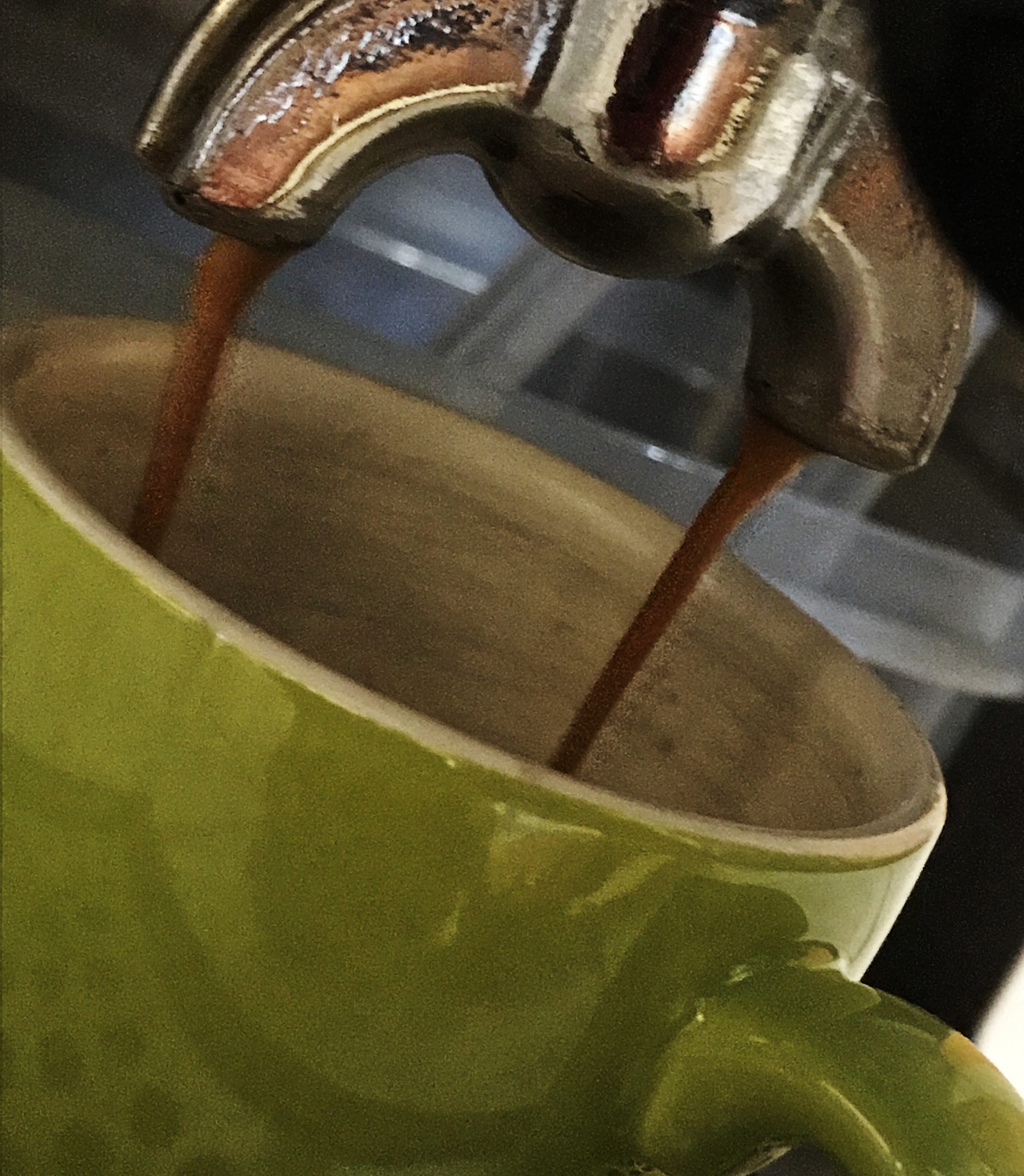 Espresso läuft aus der Siebträgermaschine in eine grüne Tasse